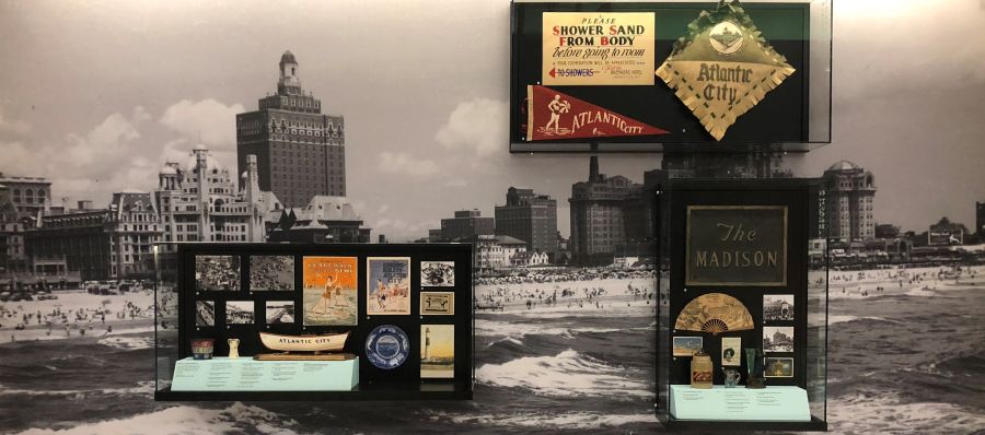Photograph of Beach and Boardwalk exhibit cases with photographs and artifacts depicting a sand pail, boat, souvenirs, and hotels.